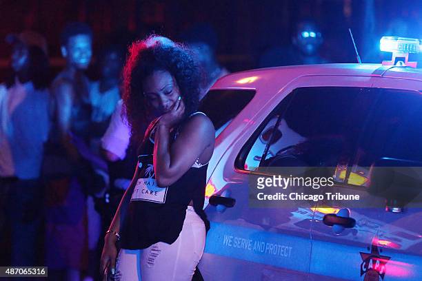 Woman leans against a police squad car as she grieves at the scene where five people were shot, including a 22-year-old man who was killed, in the...