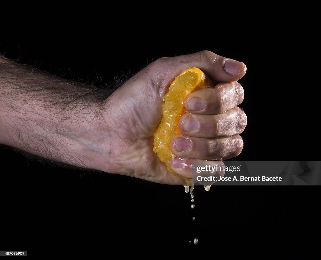 Hand squeezing orange with medium strength