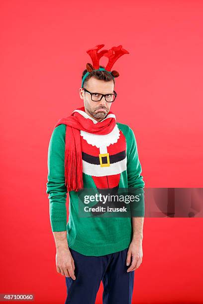 sad nerd man in funny winter outfit against red background - christmas angry stock pictures, royalty-free photos & images