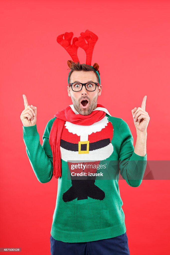 Surprised nerd man in funny winter outfit against red background