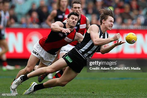 Tom Langdon of the Magpies handpasses the ball ahead of Ben Howlett of the Bombers during the 2015 AFL round 23 match between the Collingwood Magpies...