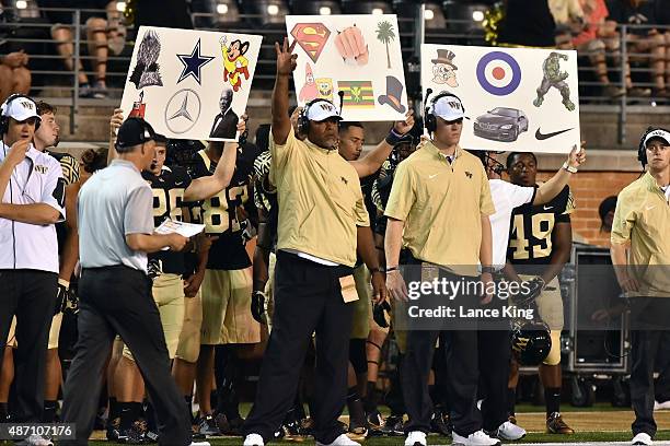 Players and team personnel of the Wake Forest Demon Deacons signal a play from the sideline during their game against the Elon Phoenix at BB&T Field...