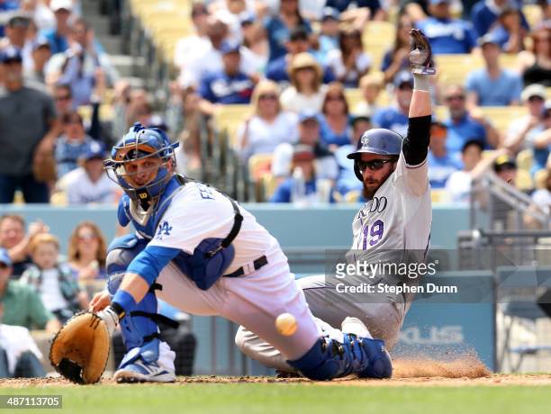 Charlie Blackmon of the Colorado Rockies slides past catcher Tim Federowicz of the Los Angeles Dodgers to score a run from third base after Rockies...