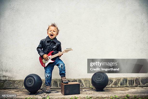 kleiner junge spielt e-gitarre - young boy enjoying music stock-fotos und bilder