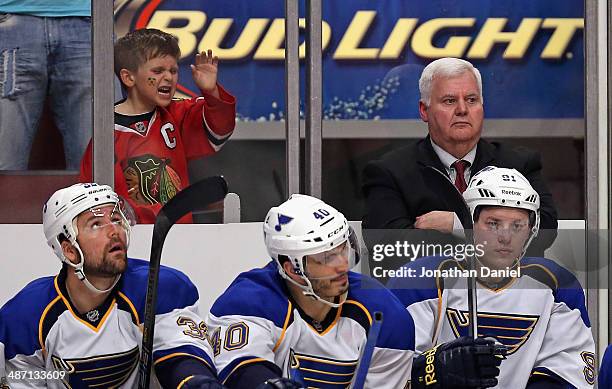 Young fan pounds on the glass as head coach Ken Hitchcock of the St. Louis Blues watches the finals minutes along with team members on the bench...