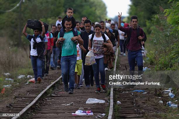 Migrants and refugees celebrate as they cross the border from Serbia into Hungary along the railway tracks close to the village of Roszke on...