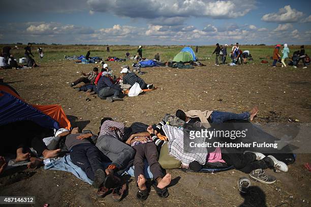 Exhausted migrants rest in a holding area after crossing the border from Serbia into Hungary along the railway tracks close to the village of Roszke...