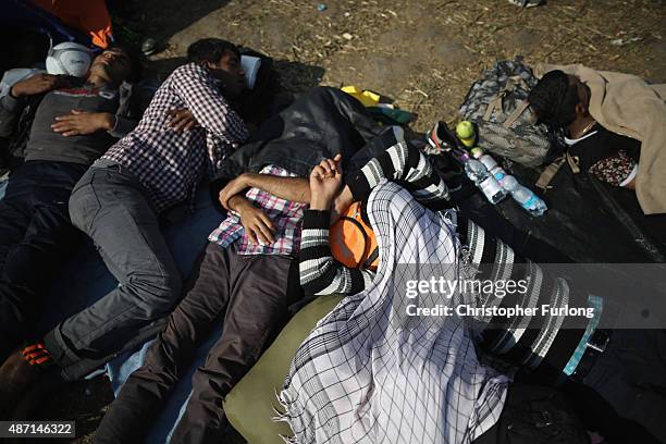 Exhausted migrants rest in a holding area after crossing the border from Serbia into Hungary along the railway tracks close to the village of Roszke...