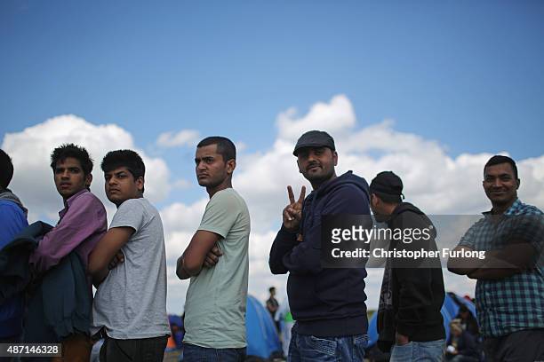 Exhausted migrants queue up in a holding area for food and water after crossing the border from Serbia into Hungary along the railway tracks close to...