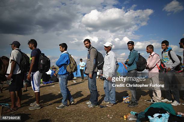 Exhausted migrants queue up in a holding area for food and water after crossing the border from Serbia into Hungary along the railway tracks close to...