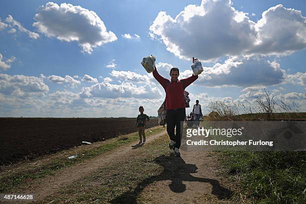 Migrants and refugees celebrate as they cross the border from Serbia into Hungary along the railway tracks close to the village of Roszke on...