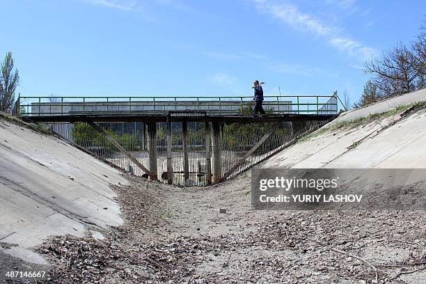 Picture taken in the Crimea's Kirovsky region on April 27 shows a man walking on a bridge across the dry Northern Crimean Canal, which supplies the...