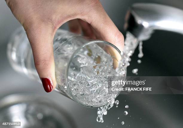 Woman fills in a glass of water on April 27, 2014 in Paris. AFP PHOTO / FRANCK FIFE
