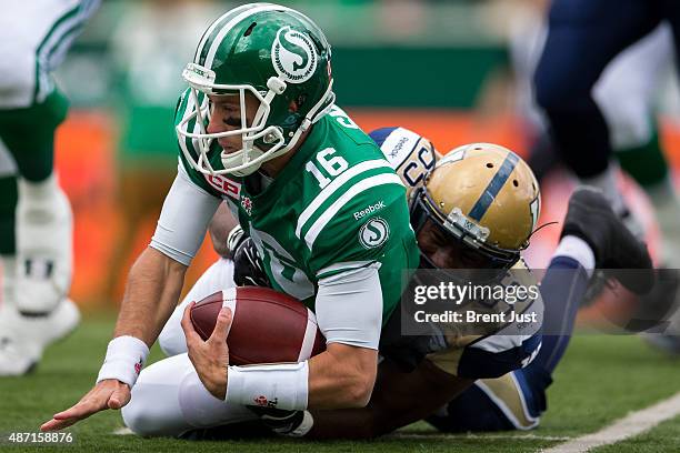 Brett Smith of the Saskatchewan Roughriders is tackled by Jamaal Westerman of the Winnipeg Blue Bombers after scrambling in the game between the...