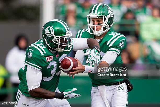 Brett Smith hands the ball to Jerome Messam of the Saskatchewan Roughriders in the game between the Winnipeg Blue Bombers and Saskatchewan...