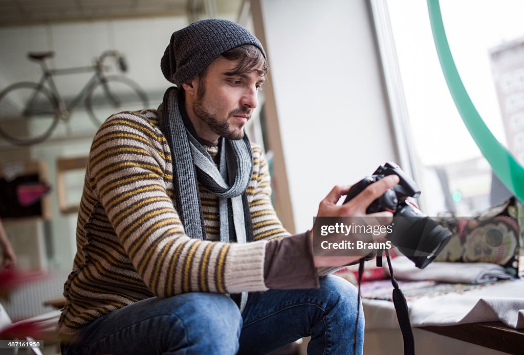 Young photographer looking at photos on digital camera.