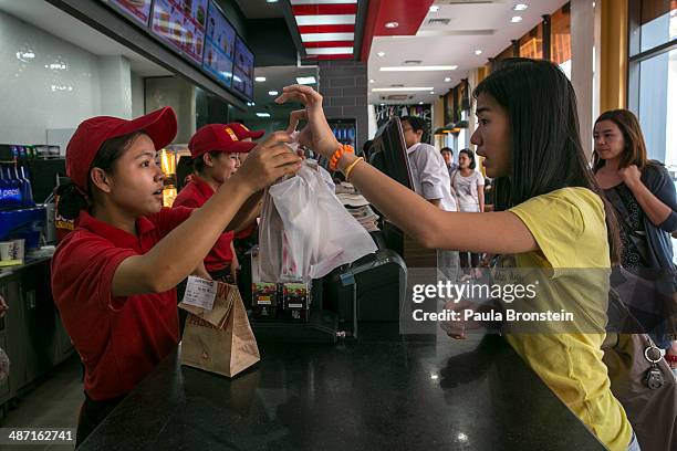 Burmese walk by the new Lotteria restaurant, a large chain of fast-food restaurants April 19, 2014 in Yangon, Myanmar. The Lotteria chain has outlets...