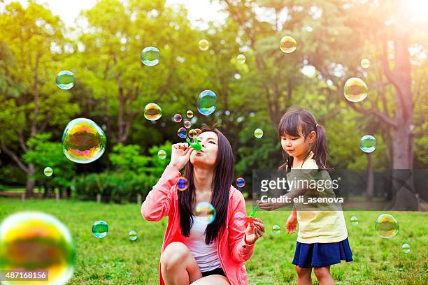mutter und tochter spaß im park mit soap bubbles - in a japanese garden stock-fotos und bilder
