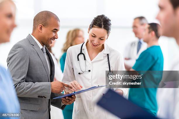 doctor and african american businessman reading documents together. - medical administrator stock pictures, royalty-free photos & images