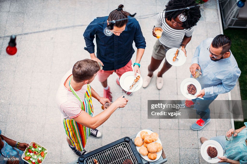 Happy Young People Eating At Barbecue Party.