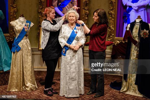 Stylists Jane Anderson and Luisa Compabassi pose with the re-styled wax figure of Britain's Queen Elizabeth II, during a photocall at Madame Tussauds...