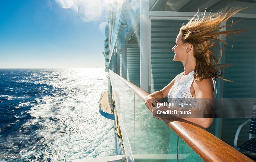 Happy woman looking at sea from a cruise ship.