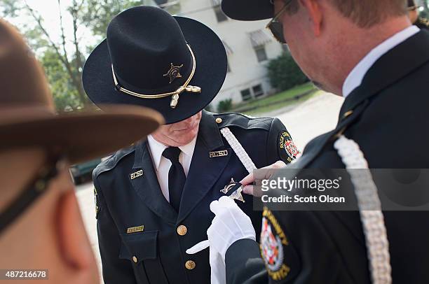 Fellow officer adjusts the mouring band on the badge of Rock County Police oficer Steve Seley as they arrive for the visitation and funeral of slain...