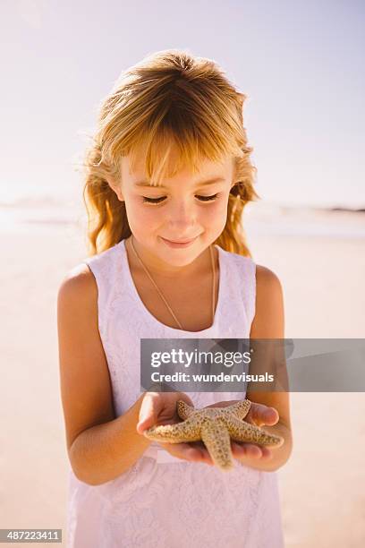 girl holding starfish in hands - starfish holding hands stock pictures, royalty-free photos & images