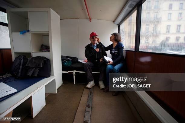 Volunteer explains to a man how to use a hearing aid in a bus of the association ''Les Enfants du Canal'' on April 28, 2014 in Paris. The operation...