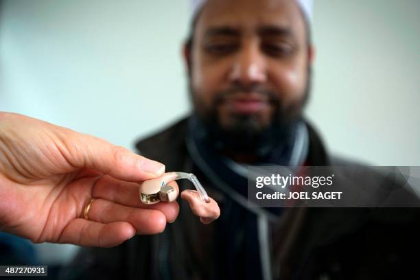 Volunteer explains to a man how to use a hearing aid in a bus of the association ''Les Enfants du Canal'' on April 28, 2014 in Paris. The operation...
