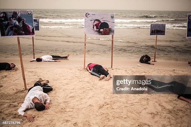 People lie on the Gaza beach to commemorate Aylan Kurdi, the three-year-old boy dressed in shorts and a red T-shirt, and 12 Syrians who drowned in...