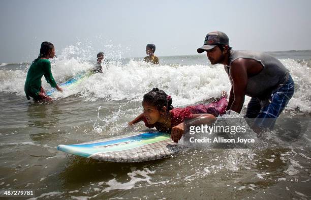 Rashed Alam teaches 12 year old Shuma to surf April 12, 2014 in Cox's Bazar, Bangladesh. A group of 10-12 year old female beach vendors, most of whom...