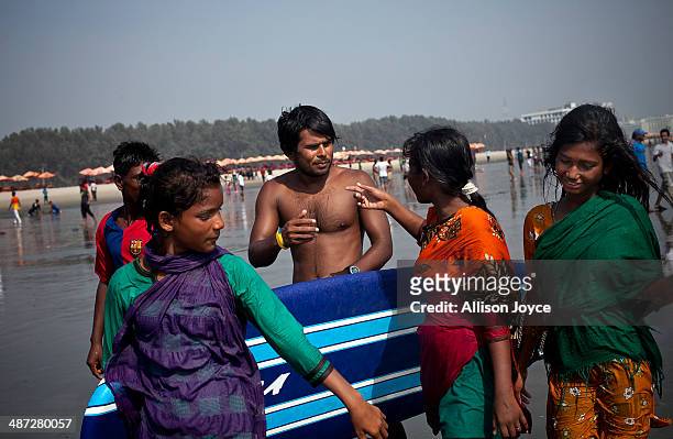 Rashed Alam talks with beach vendors after surfing April 14, 2014 in Cox's Bazar, Bangladesh. A group of 10-12 year old female beach vendors, most of...