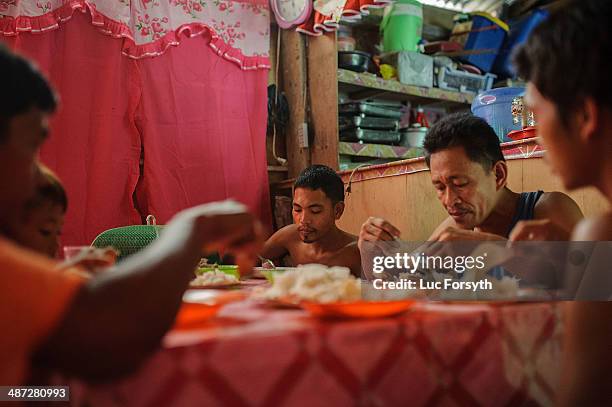 Gold miners and their family eat dinner together in a small house built near their mountainside camp. Many miners have homes in the nearby village of...