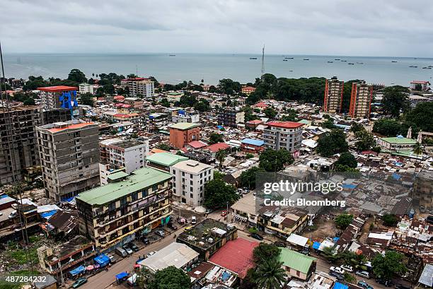 Shipping vessels sit on the waterway beyond commercial and residential buildings on the city skyline in Conakry, Guinea, on Saturday, Sept. 5, 2015....