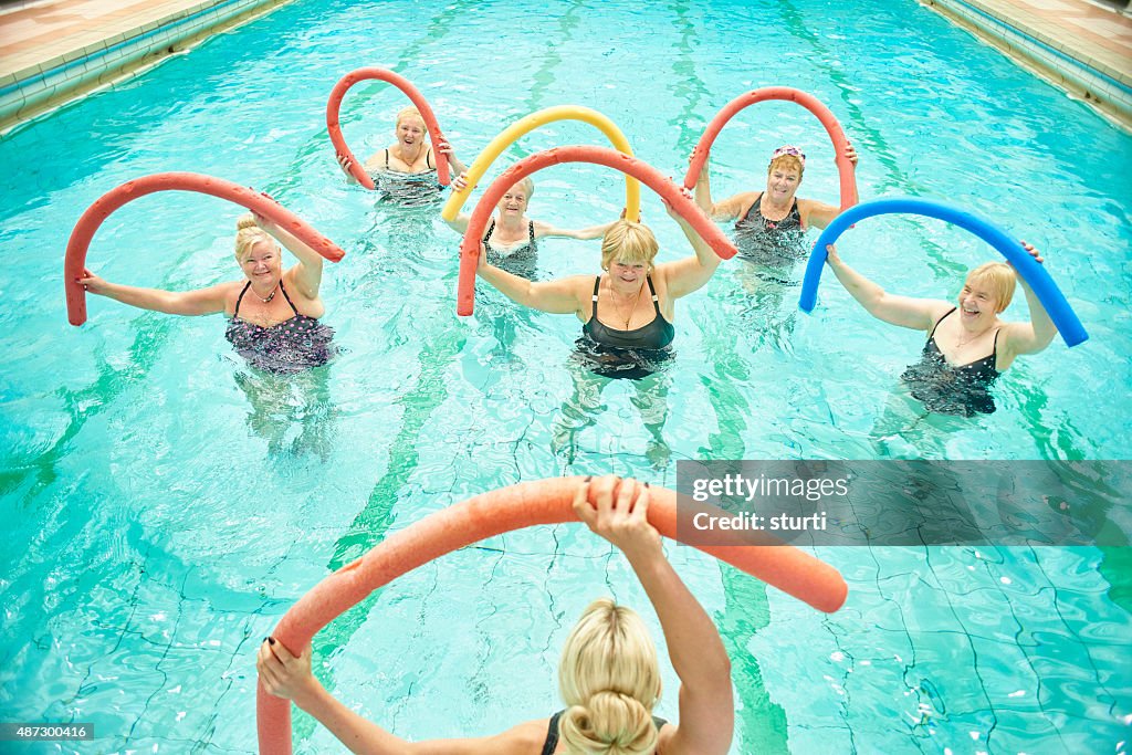 Senior women led by female instructor at water aerobics