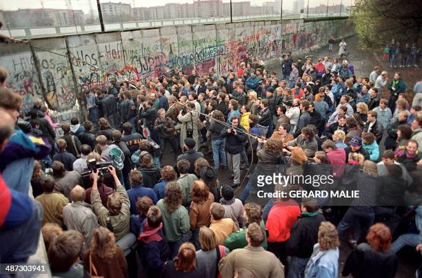 West Berliners crowd in front of the Berlin Wall early 11 November 1989 as they watch people trying to demolish a section of the wall in order to...