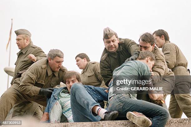 Berliners confront with East German policemen atop the Berlin Wall early 11 November 1989, near the Potsdamer Square. Two days before, Gunter...
