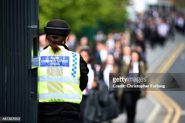 Police community support officer stands guard outside Corpus Christi Catholic College in Neville Road, as children leave at the end of the day on...