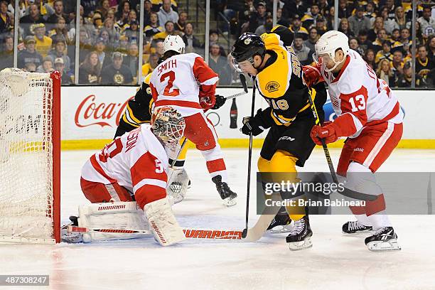 Reilly Smith of the Boston Bruins fights for the puck against Jonas Gustavsson and Pavel Datsyuk of the Detroit Red Wings in Game Five of the First...