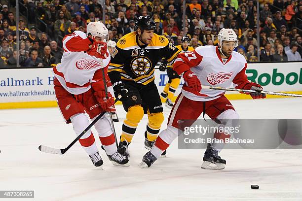 Milan Lucic of the Boston Bruins skates after the puck against Brendan Smith and Kyle Quincey of the Detroit Red Wings in Game Five of the First...