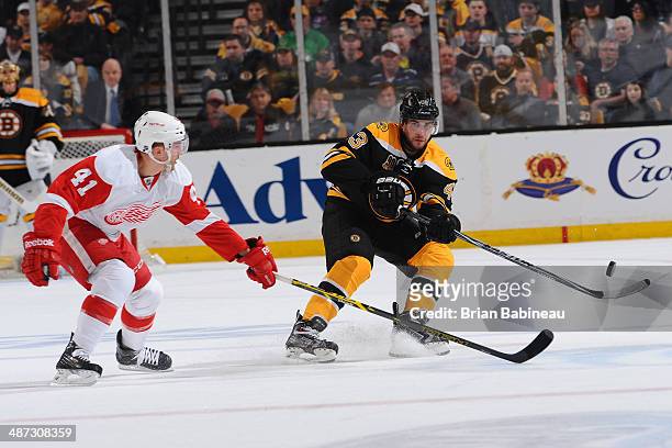 Matt Bartkowski of the Boston Bruins passes the puck against Luke Glendening of the Detroit Red Wings in Game Five of the First Round of the 2014...