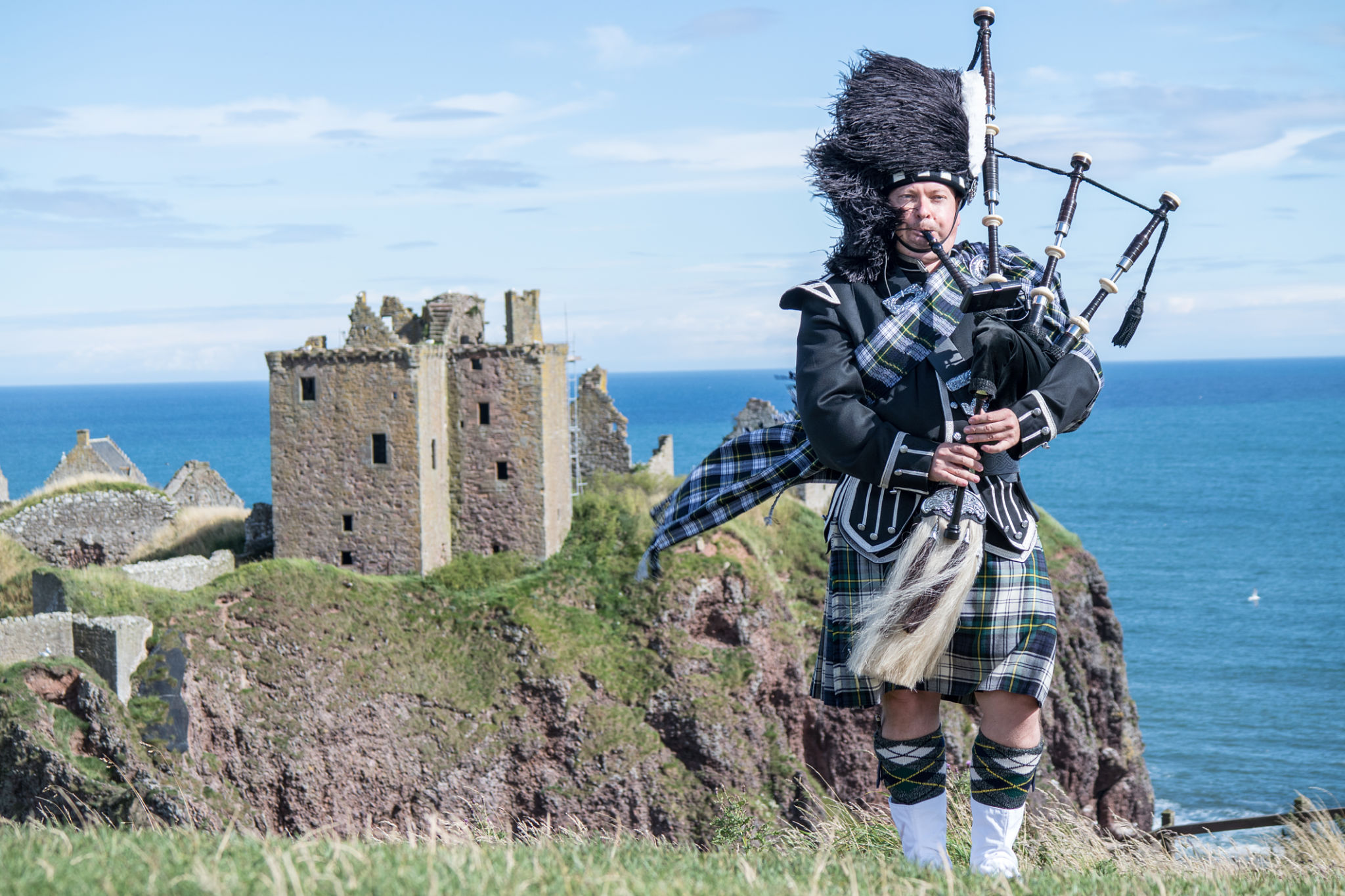Traditional scottish bagpiper at Dunnottar Castle Traditional scottish bagpiper at Dunnottar Castle