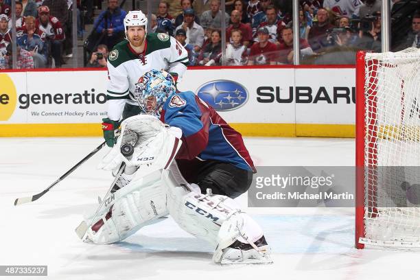Goaltender Semyon Varlamov of the Colorado Avalanche makes a glove save as Kyle Brodziak of the Minnesota Wild looks on in Game Five of the First...