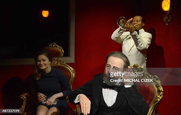 Guest poses next to wax statues featuring Czech music composer Bedrich Smetana and US jazz trumpeter and singer Louis Armstrong during the official...