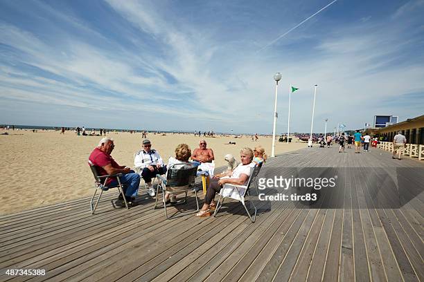 group of seniors sitting on beach promenade at deauville - deauville beach stock pictures, royalty-free photos & images