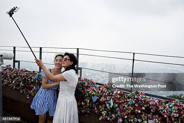 Tourists take selfie with a selfie stick at the observation deck at N Seoul Tower on the top of Namsan mountain on Jul. 29, 2015 in Seoul, South...