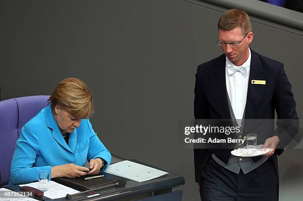 German Chancellor Angela Merkel uses her mobile phone as she attends a session of the Bundestag, the German parliament, on September 9, 2015 in...