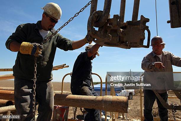 Jose Marquez, Israel Garcia and John Hicks with Arthur & Orum Well Drilling prepare to install a new drill pipe on a rig drilling a well at a farm on...