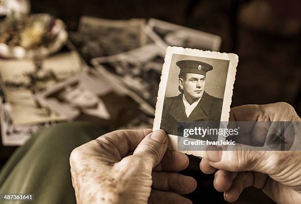 senior woman holding dear photograph of her husband - death photos stockfoto's en -beelden